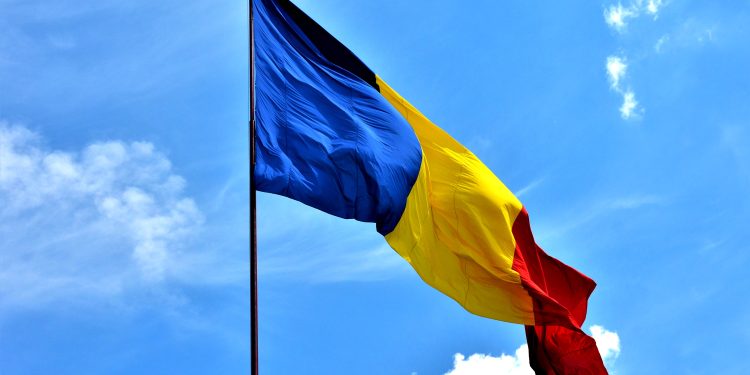A closeup shot of the Romanian flag fluttering in the wind against a blue clear sky